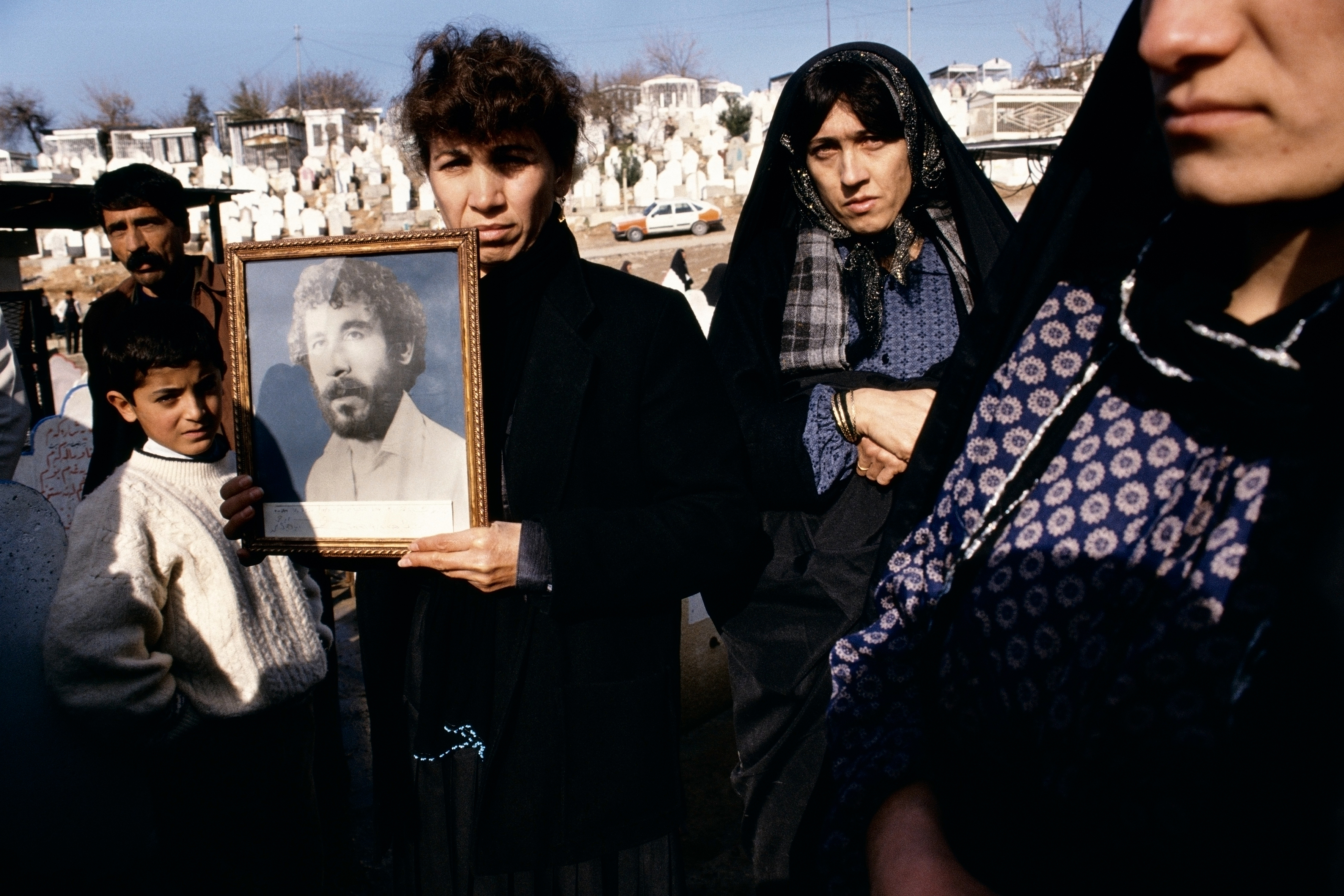 Susan Meiselas Photographs of 20-year-old Kamaran Abdullah Saber are held by his family at Saiwan Hill cemetery. He was killed in July 1991 during a student demonstration against Saddam Hussein, Kurdistan, Northern Iraq, 1991. Â© Susan Meiselas