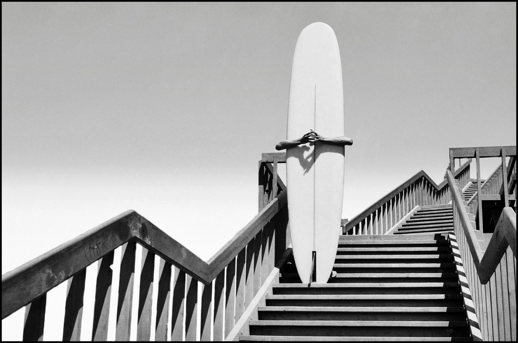 Dennis Stock, Man holding a surfboard on beach steps in Corona Del Mar, California 1968, from California Trip