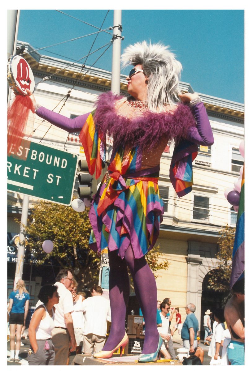 Gilbert Baker posing in a rainbow dress with a Rolling Stones tambourine during the 1987 Castro Street Fair; photograph by Robert Pruzan, collection of the GLBT Historical Society